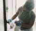Domestic work at home. One woman cleaning door in apartment with spray and gloves. Housewife